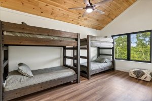 Spacious 4-bedroom cabin in Sevierville, TN, featuring a modern, rustic design with a large porch, comfortable seating area, and expansive windows. The cabin includes luxurious bedrooms, a well-equipped kitchen, a cozy living room with a fireplace, and scenic views of the surrounding mountains. The property also boasts a game room, theater room, and outdoor deck for relaxation and entertainment.