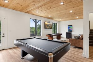 Spacious 4-bedroom cabin in Sevierville, TN, featuring a modern, rustic design with a large porch, comfortable seating area, and expansive windows. The cabin includes luxurious bedrooms, a well-equipped kitchen, a cozy living room with a fireplace, and scenic views of the surrounding mountains. The property also boasts a game room, theater room, and outdoor deck for relaxation and entertainment.