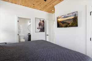 Spacious 4-bedroom cabin in Sevierville, TN, featuring a modern, rustic design with a large porch, comfortable seating area, and expansive windows. The cabin includes luxurious bedrooms, a well-equipped kitchen, a cozy living room with a fireplace, and scenic views of the surrounding mountains. The property also boasts a game room, theater room, and outdoor deck for relaxation and entertainment.